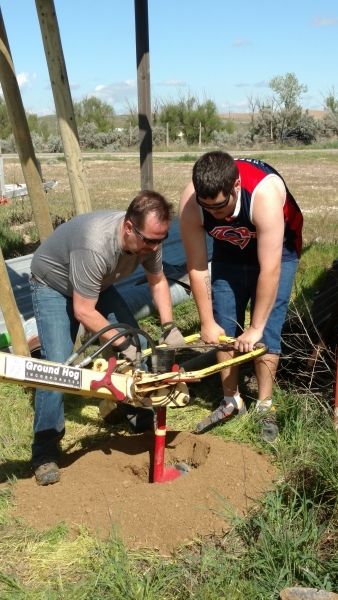 Jason helping student use the auger during fence project