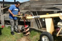 Student using auger to help with fence project